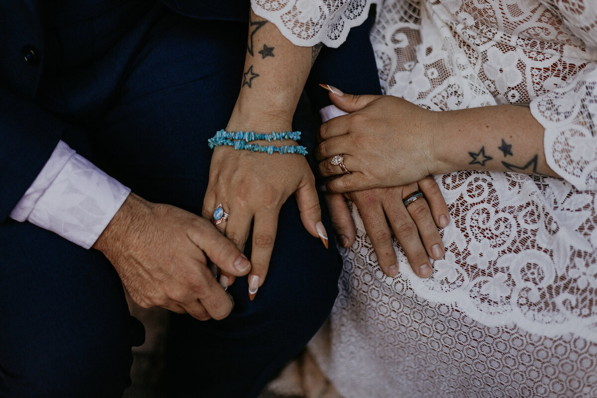 close up of bride and grooms hands and jewelry details in their lap