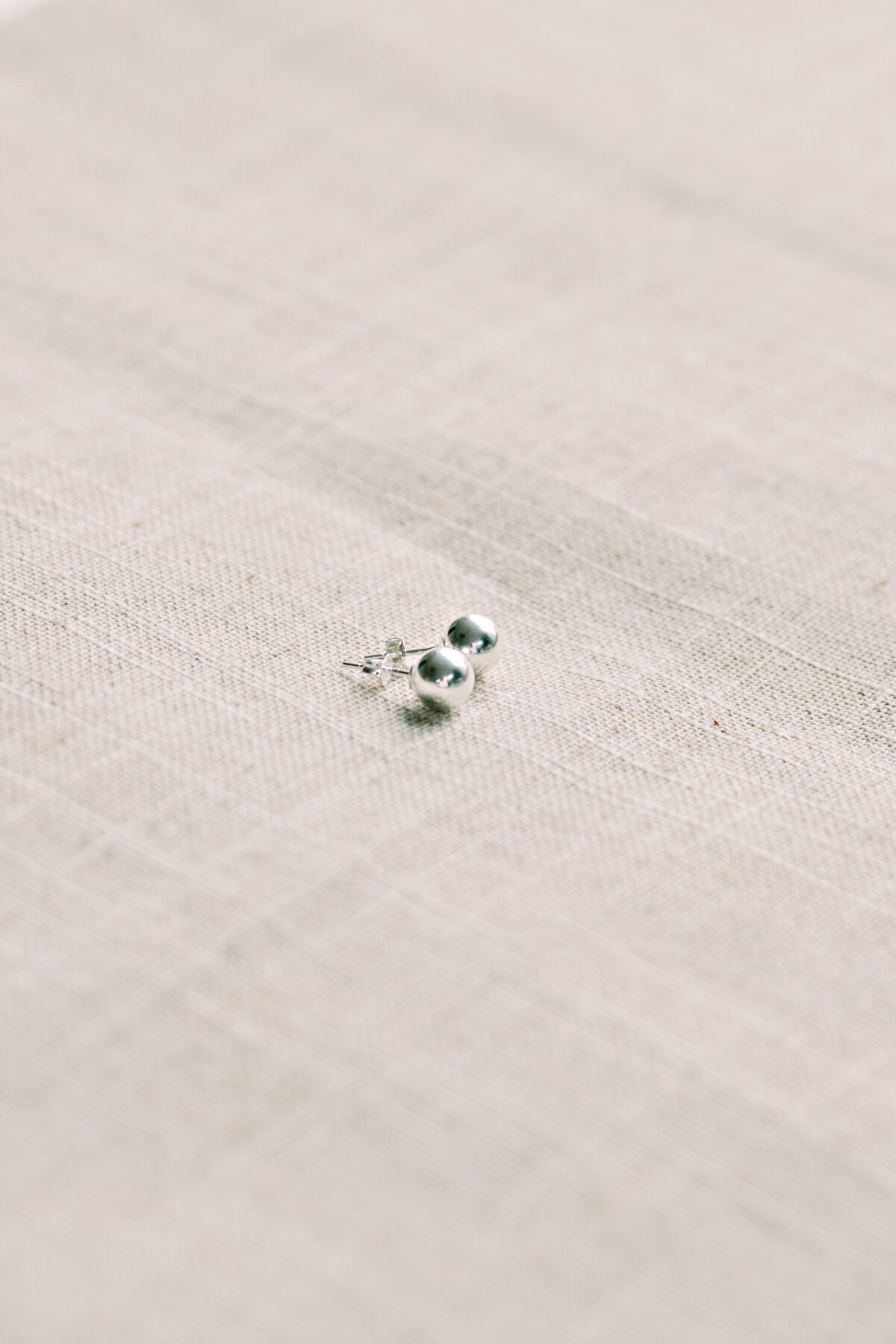 Silver earrings studs on linen 