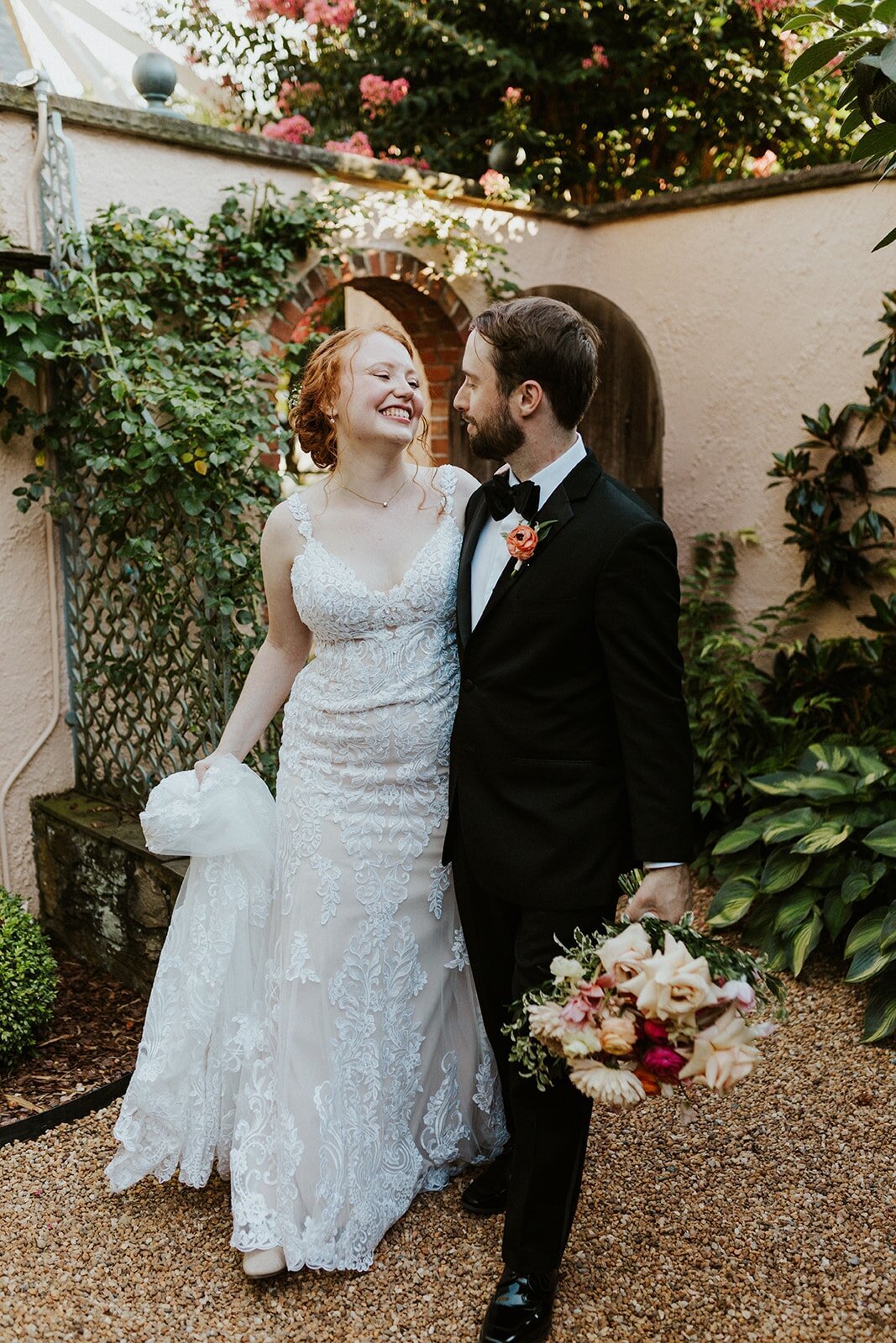 A bride and a groom walk in a garden