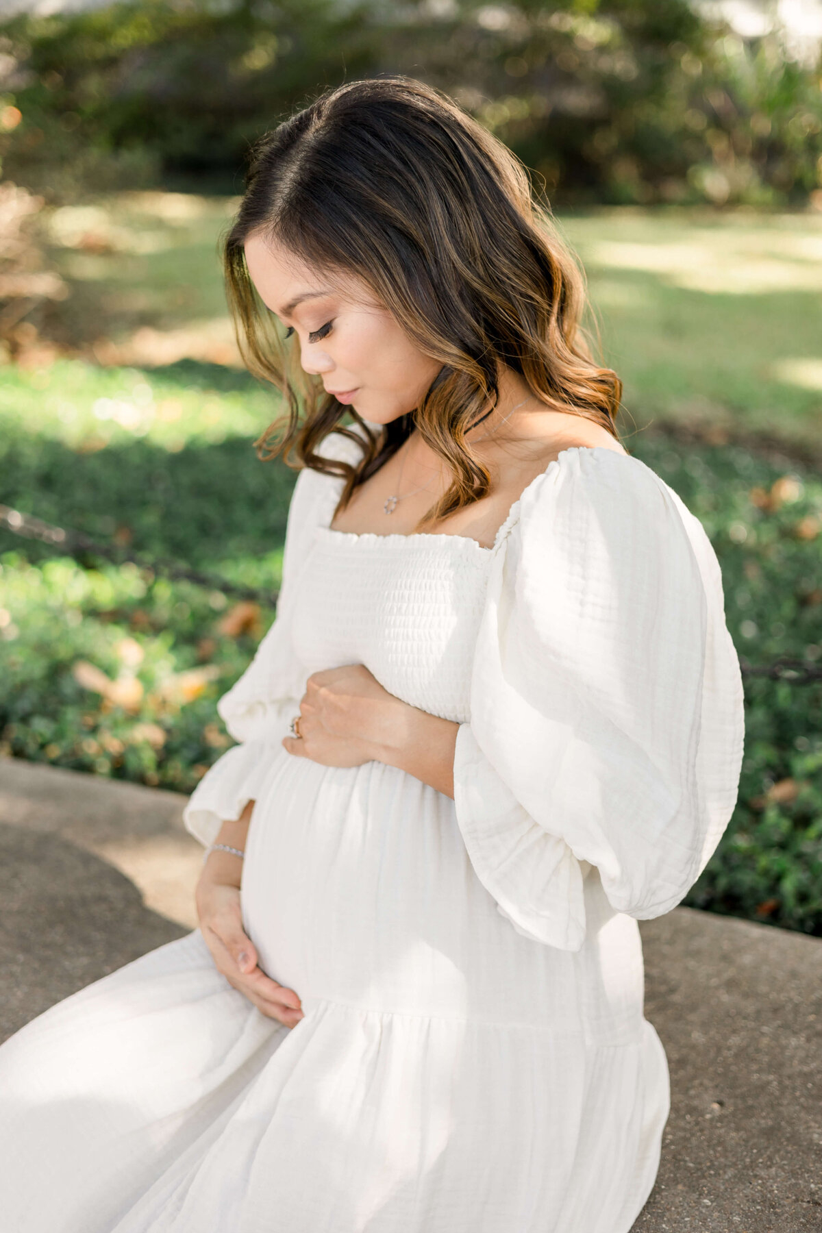 a pregnant woman sitting with her hands on her baby bump