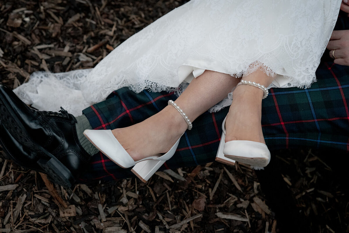Bride and Groom (in tartan troos) cross legs while sat down. 