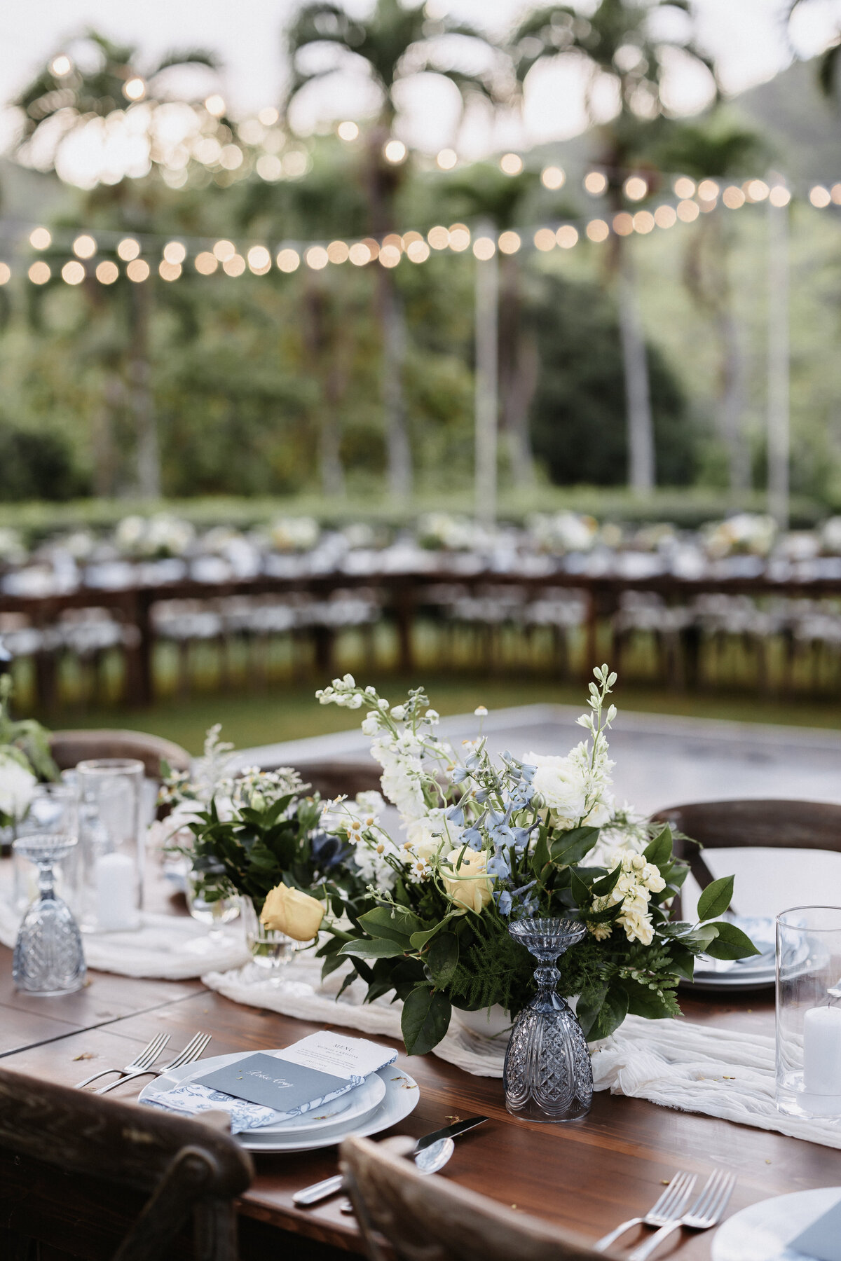Long rectangle wedding reception table on farm tables with dark wood chairs and green centerpieces