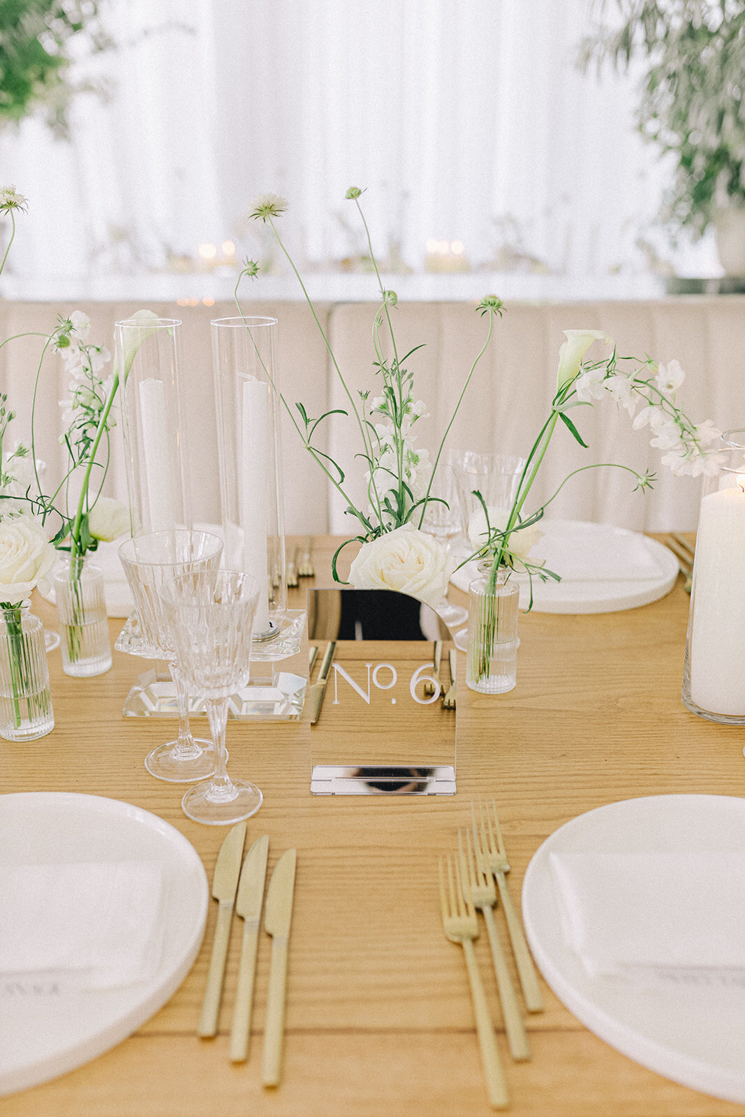 An array of bud vase centrepieces featuring white flowers and greenery for a Willow Inn wedding.