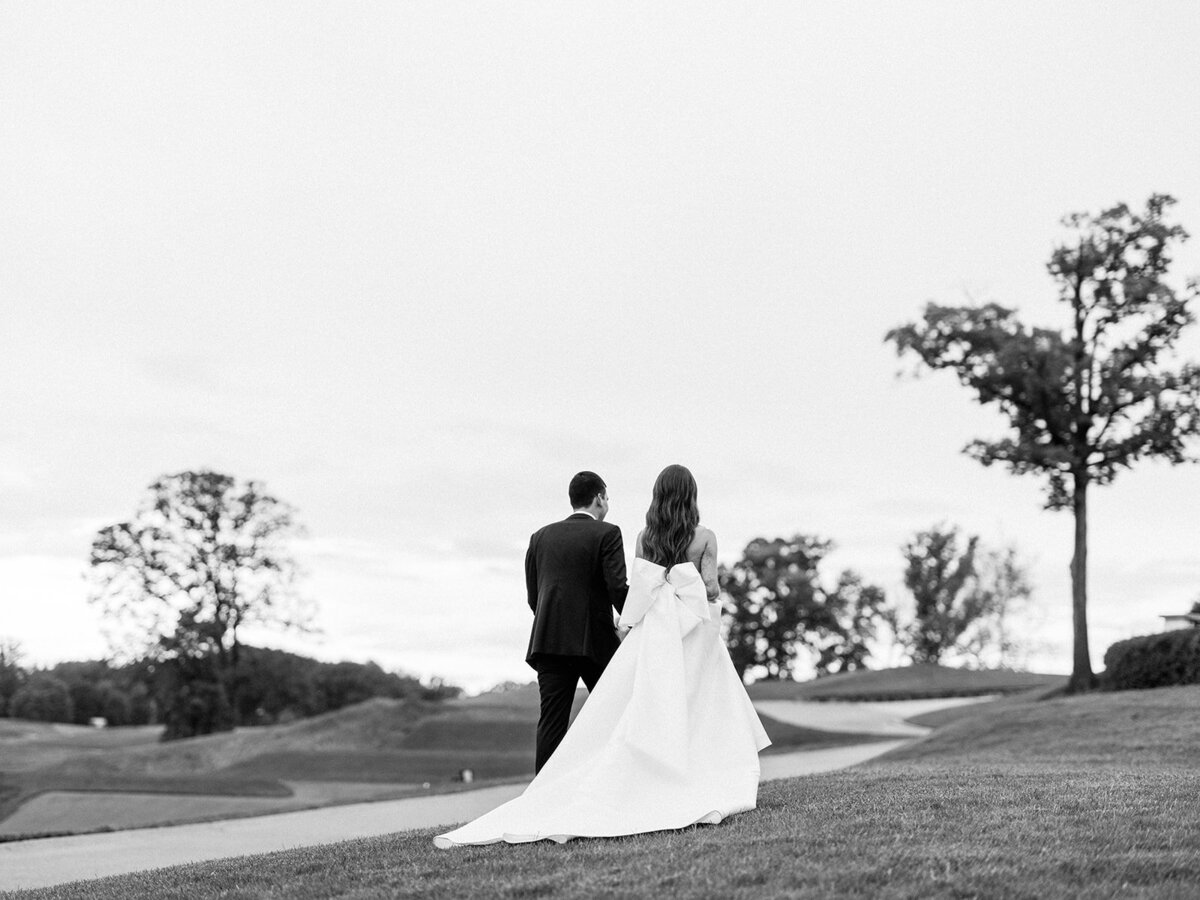 Black and white landscape image of couple walking up the hills on the golf course
