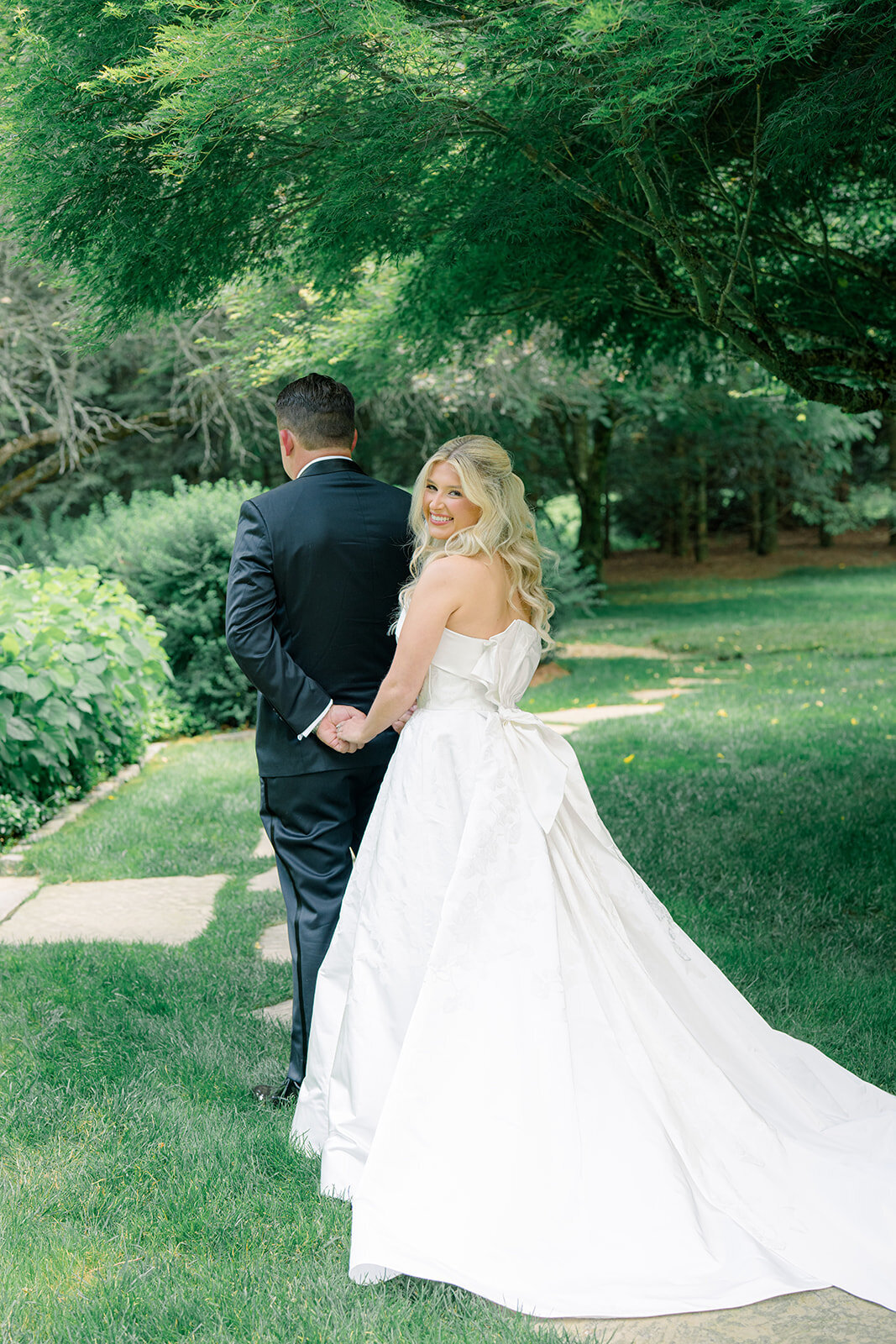 Bride approaches groom for their first look in the garden at Old Edwards Inn, with lush greenery and soft natural light.
