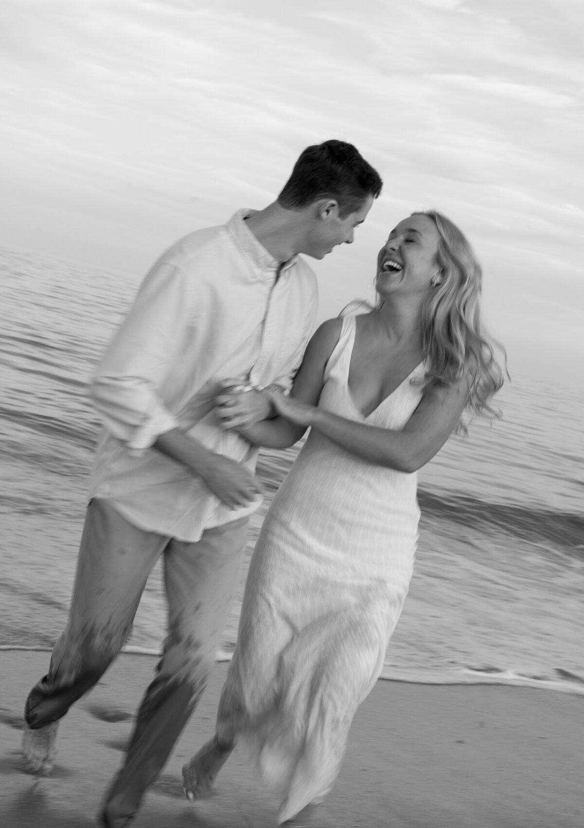 Couple running out of ocean laughing at each other by florida engagement photographer Shelby Ann Photos