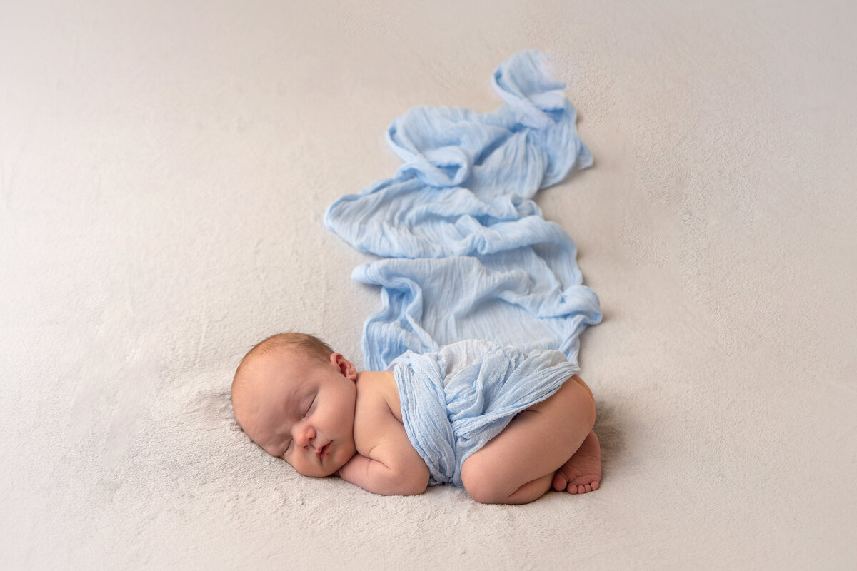 newborn-baby-psoing-in-blue-swaddle