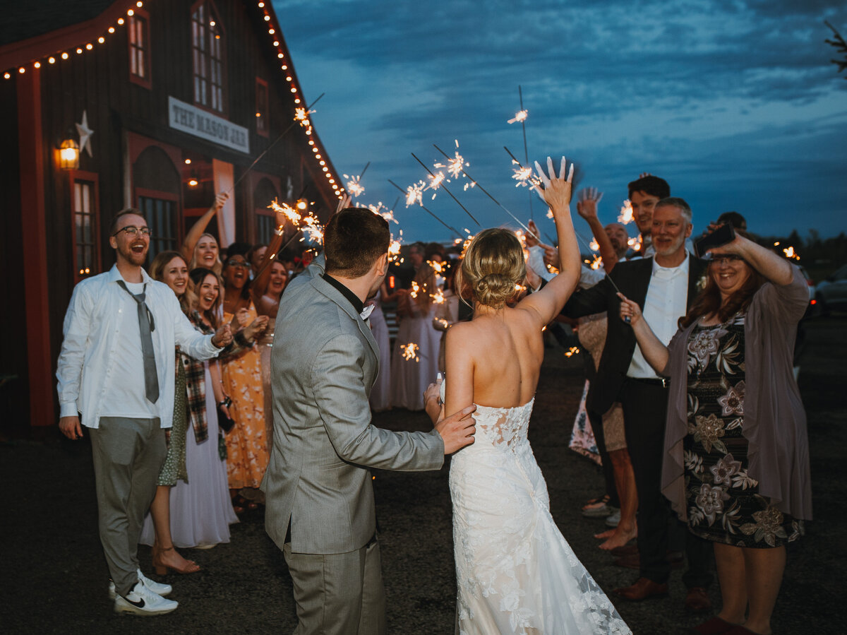 Bride and groom waving at crowd with sparklers