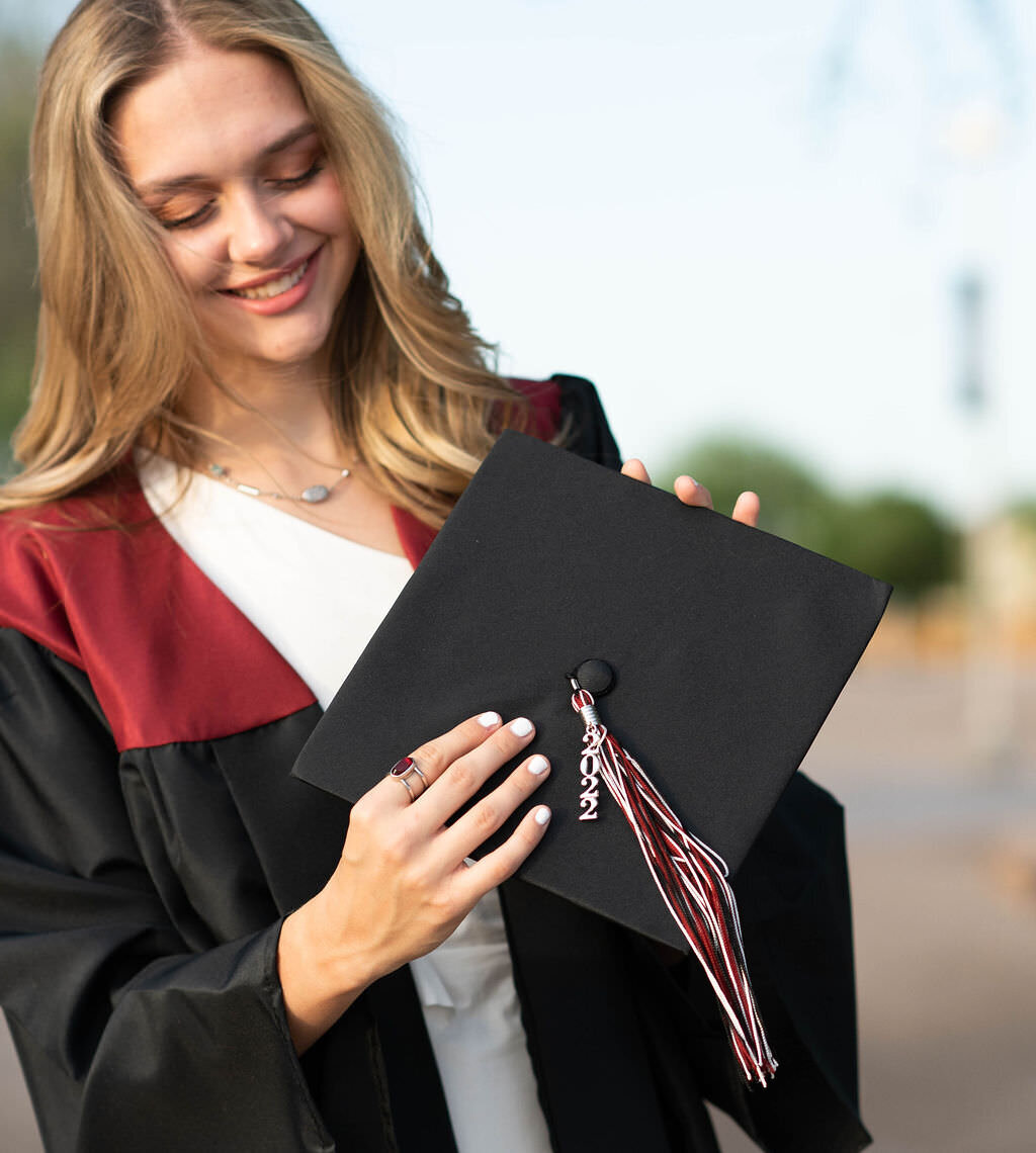 A girl smiling and looking at a graduation cap