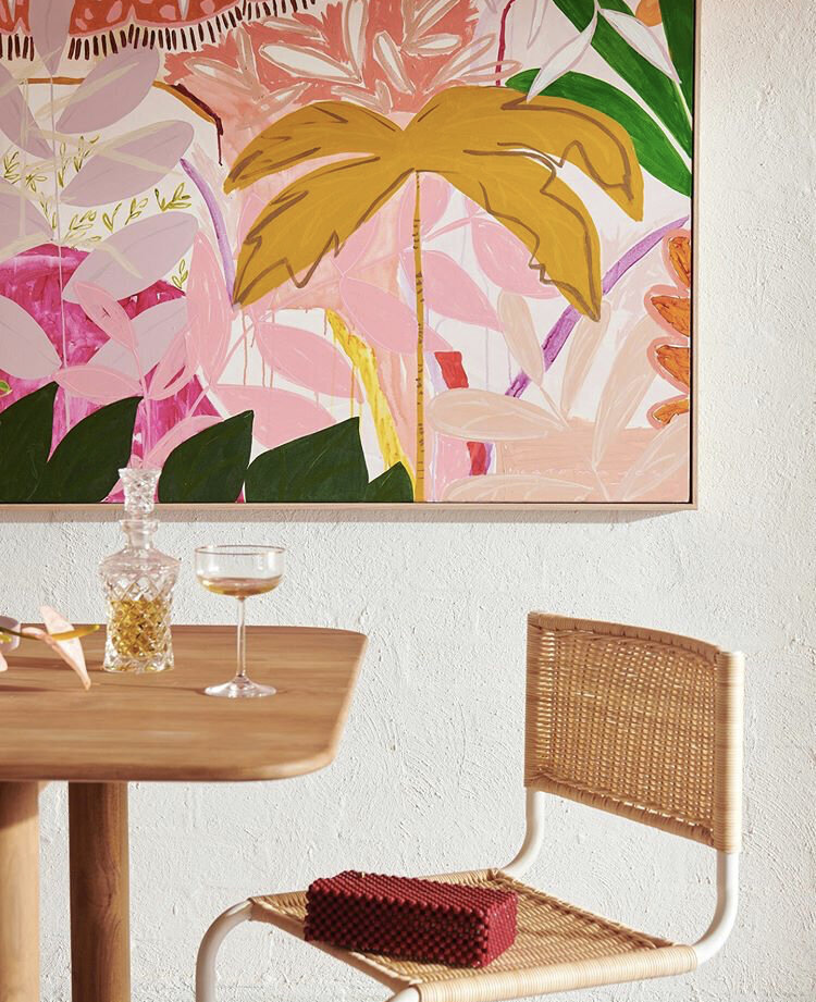 Close-up of rattan chair and timber dining table with colourful modern artwork, styled by Melbourne interior stylist Lisa Hunter Interiors.