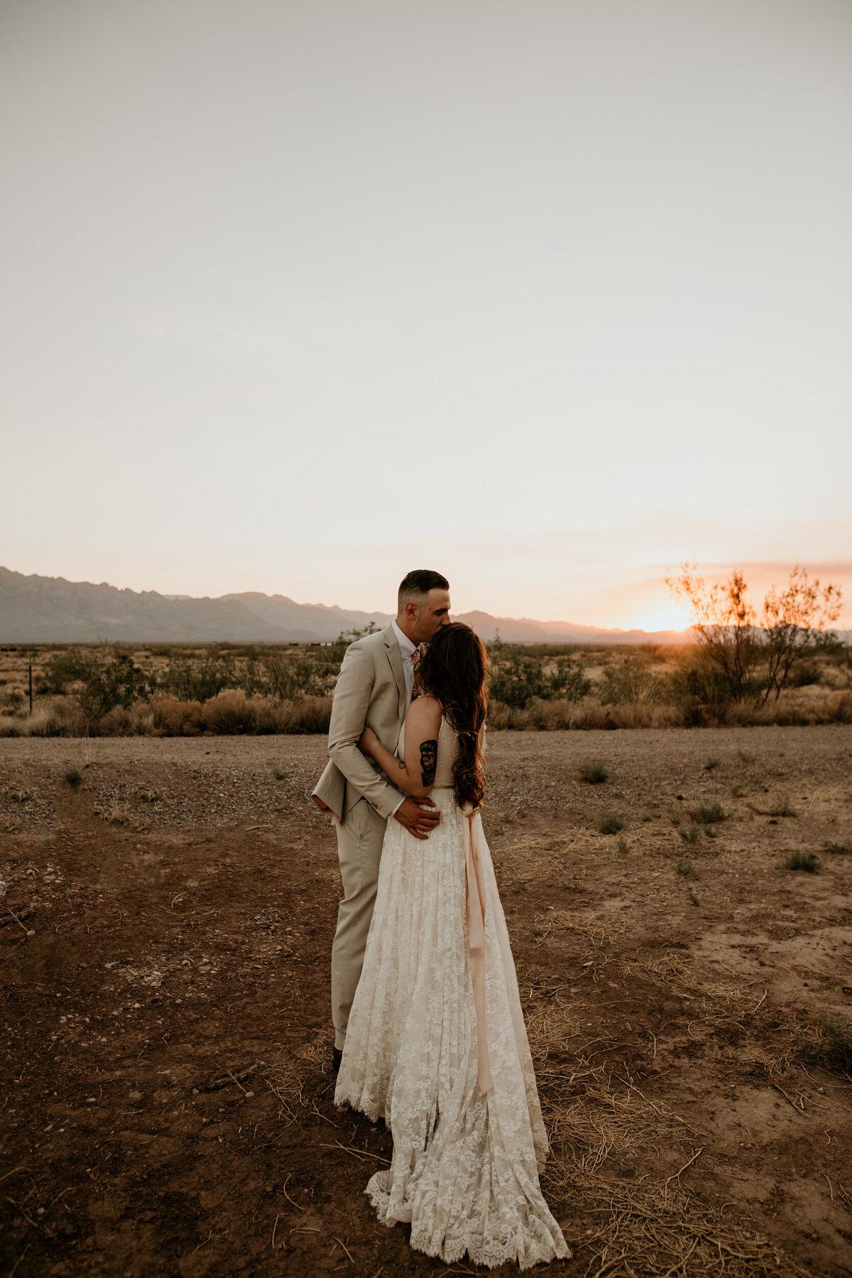 bride and groom hugging each other at sunset