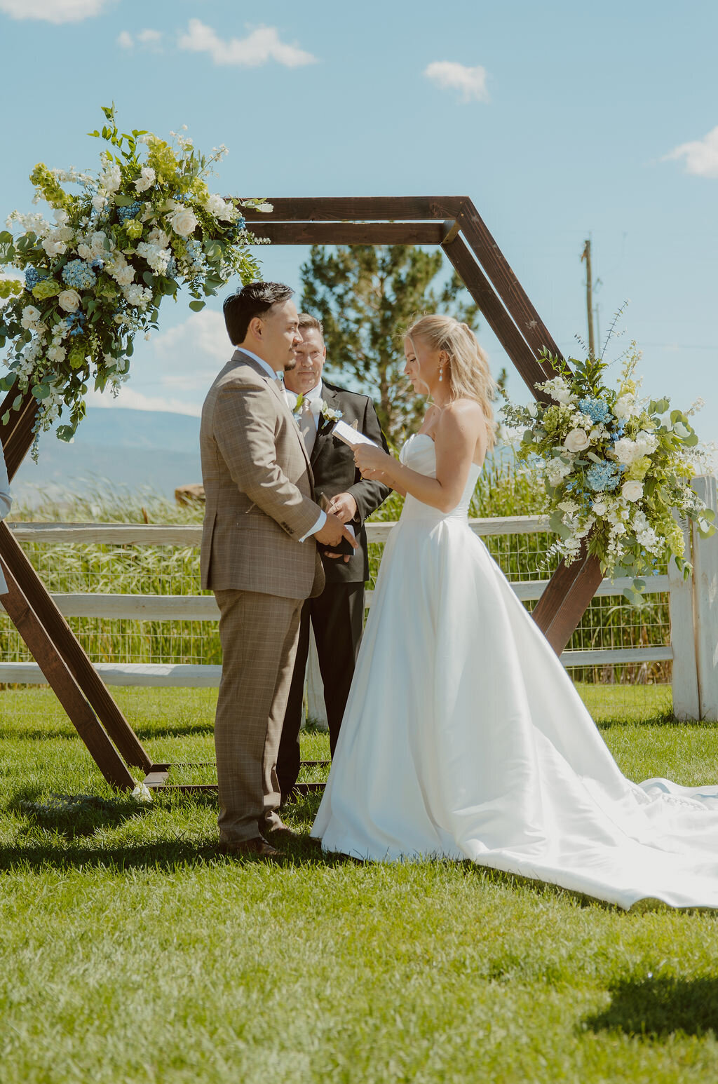 Couple exchanging vows at a hexagon arch on the lawn