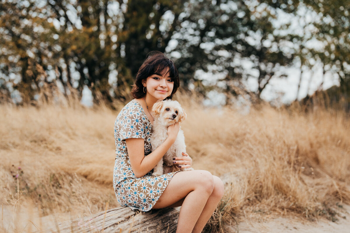 senior-girl-with-her-dog-in-a-meadow-discovery-park-seattle