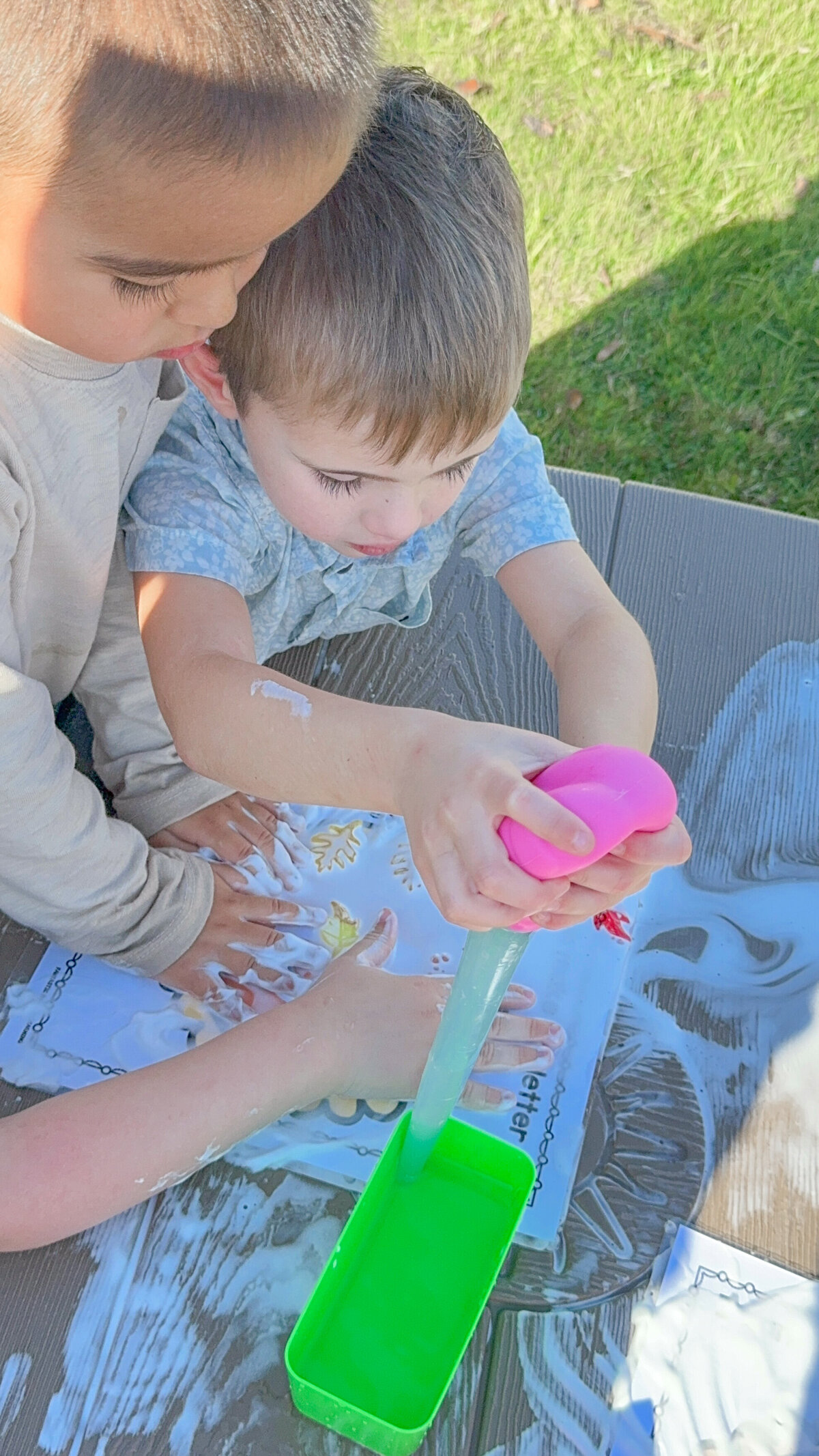 Children playing in the outdoor sensory bin with water and soap at House of Parker Preschool in Gorham Maine where we protect and nurture imagination, giving children time and freedom to explore, invent, and lead their own play.