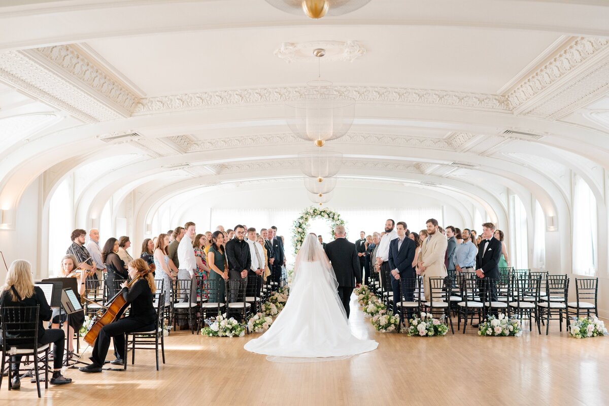 A bride walks down the aisle at her wedding ceremony at The Cottonwood Hotel in Omaha. Photo by Anna Brace, who specializes in wedding photography in Omaha Nebraska. 
