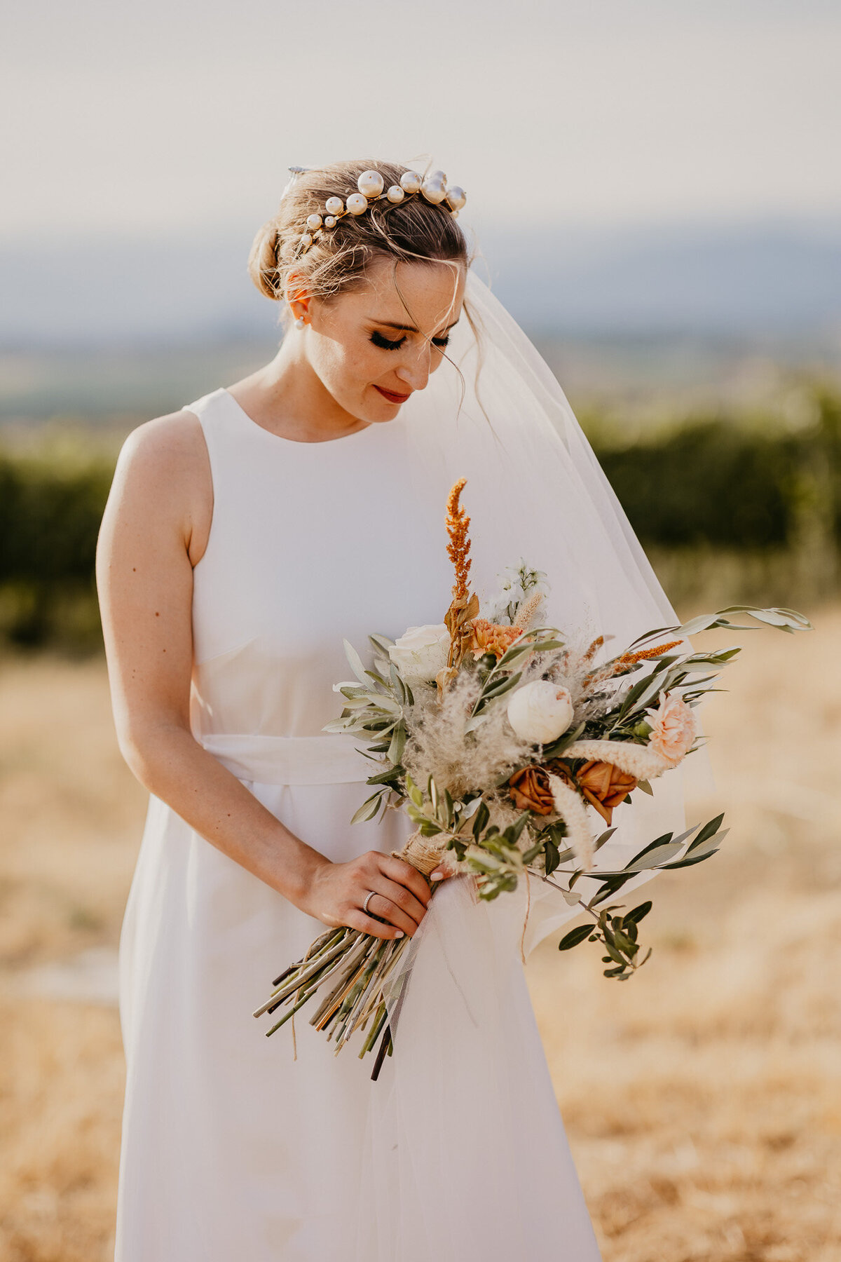 Bride holding rustic floral bouquet in vineyards near Villa Dianella, romantic Tuscany wedding photographer.