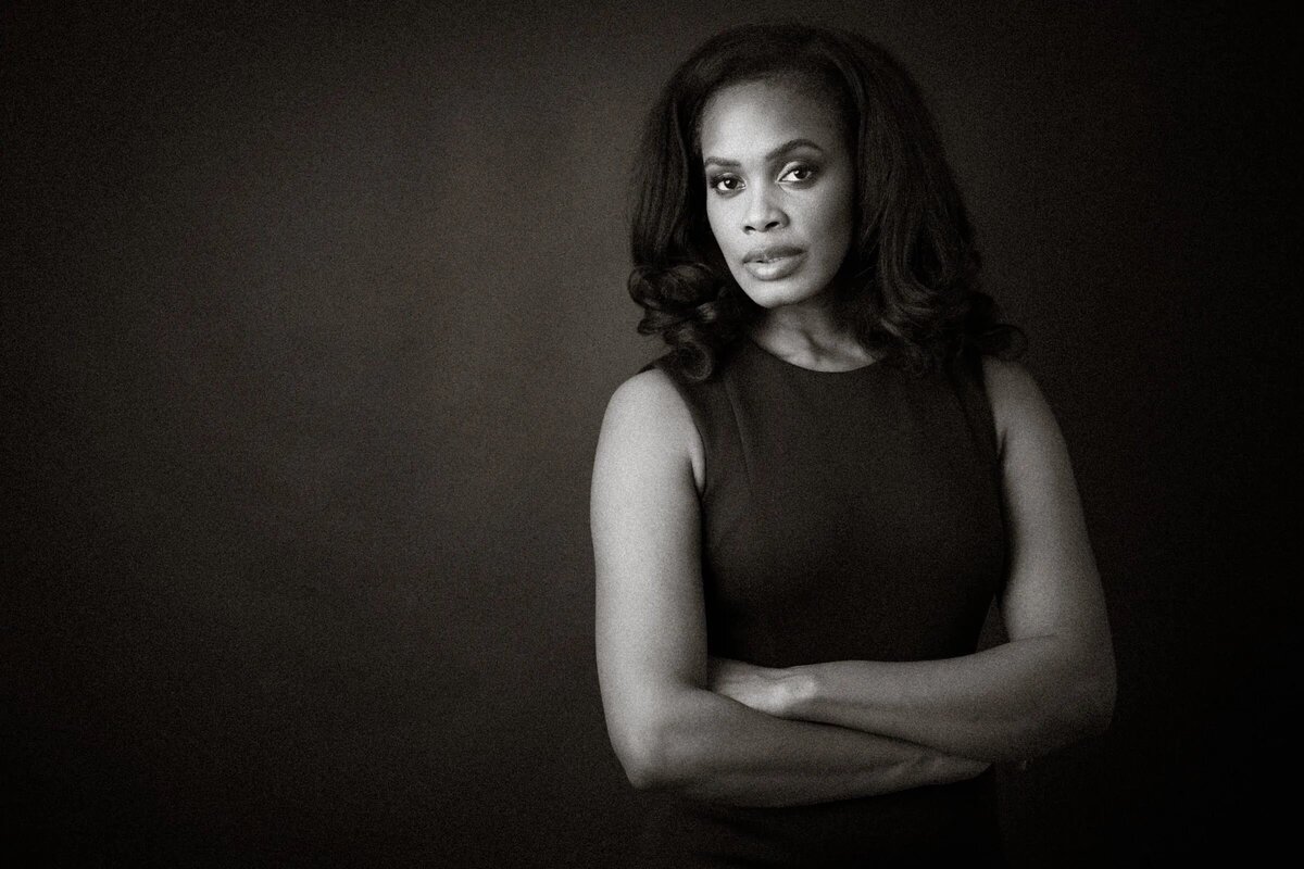 A woman with her arms crossed looking straight forward.