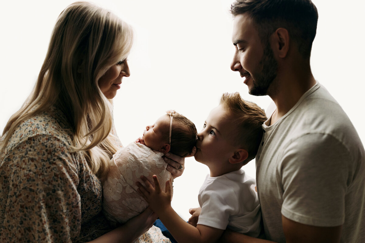 Parents with newborn baby and toddler in silhouette
