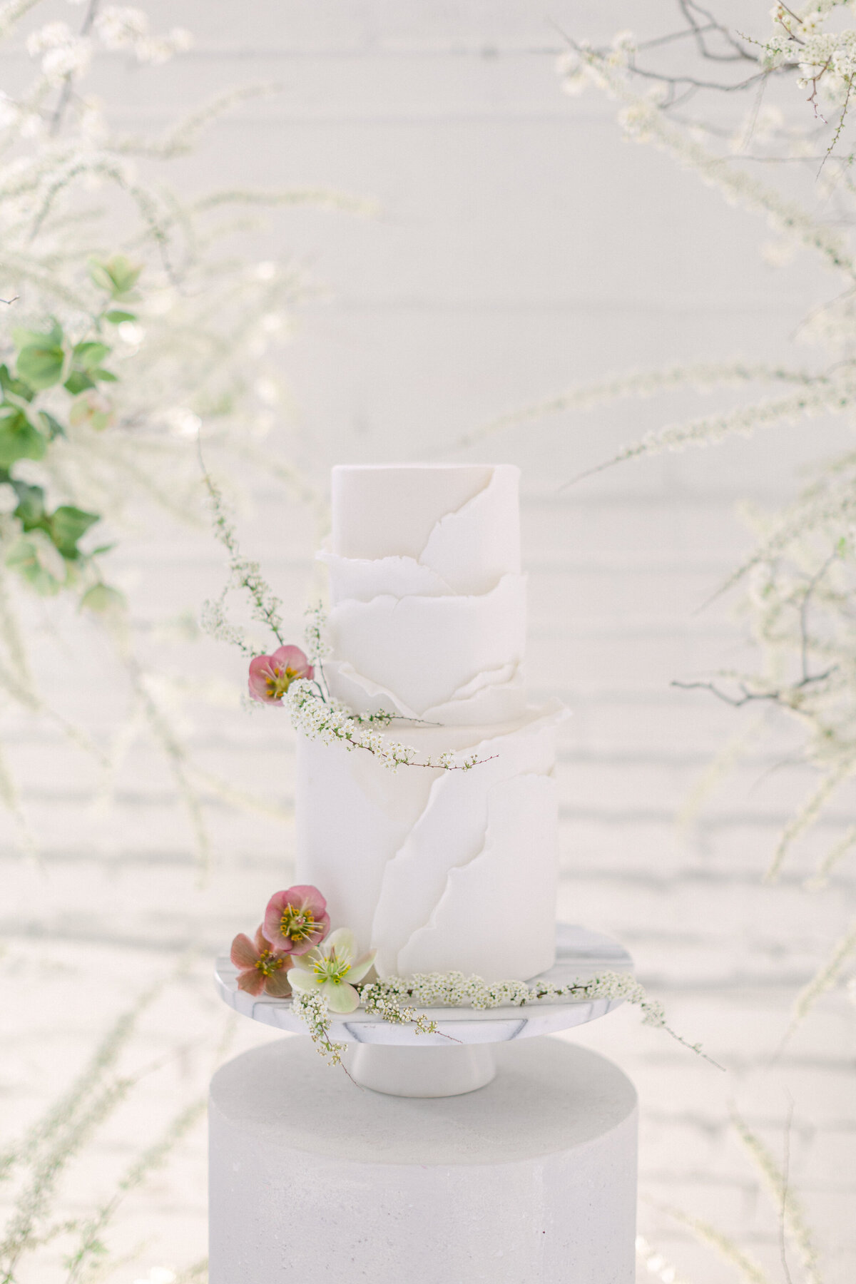 Minimalist decoration of pale, delicate flowers on a white tiered wedding cake at a Montreal studio. 
