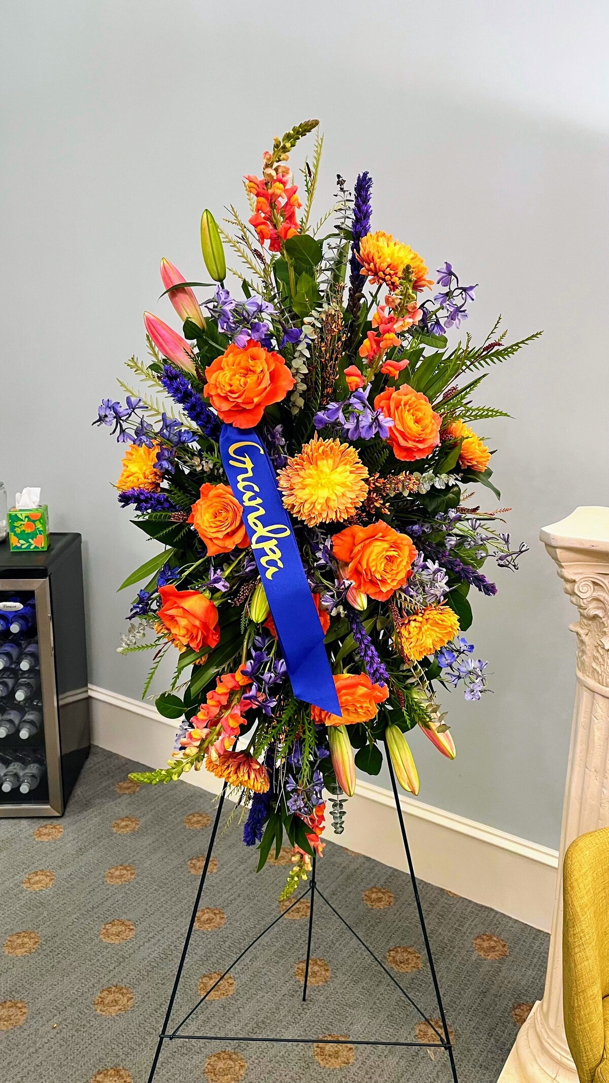 bright orange and blue funeral flower side arrangement spray 