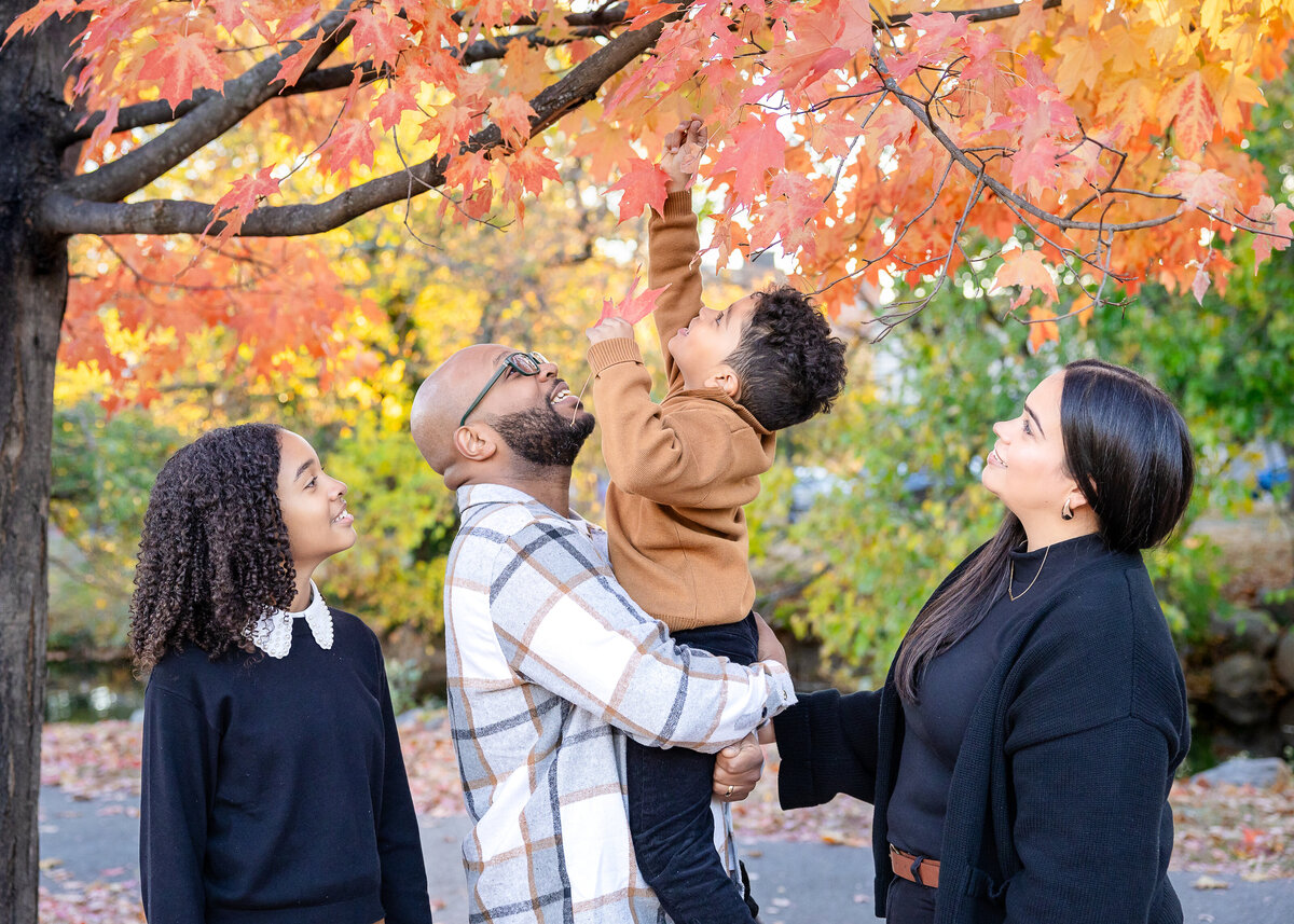Lifestyle photo of family smiling and looking at fall leaves