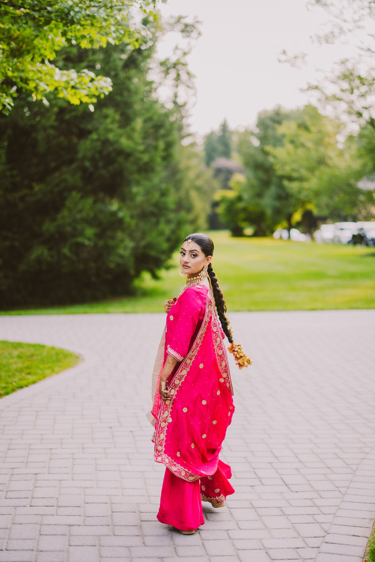 A sikh bride looking over her shoulder as she walks away at her sangeet jaago party during the wedding week in traditional punjabi outfit