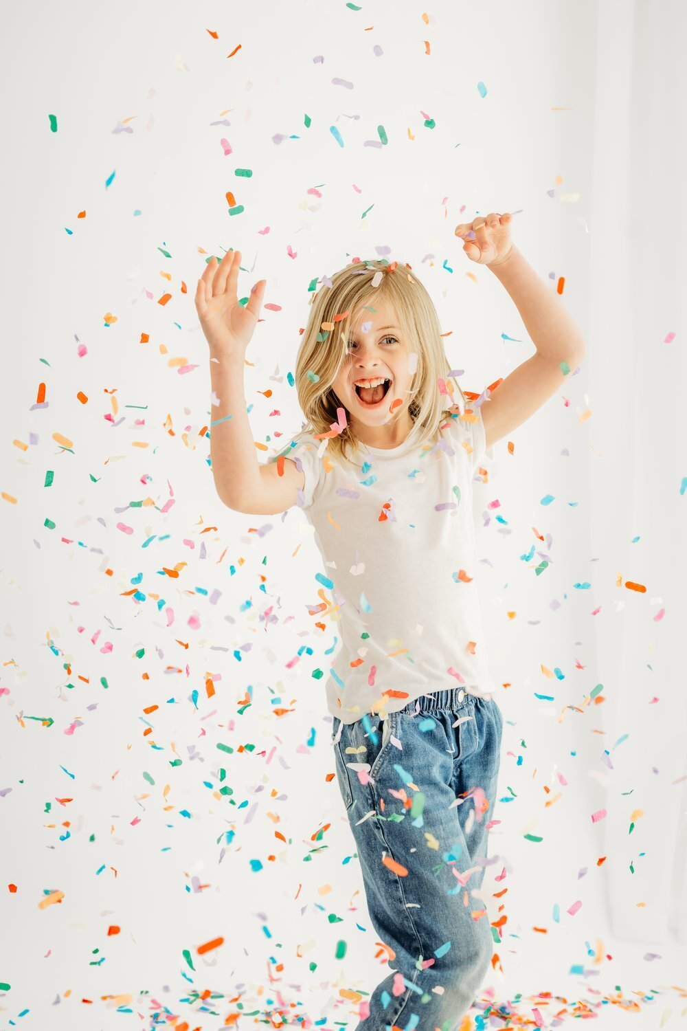 girl throws arms in the air and is surrounded by confetti