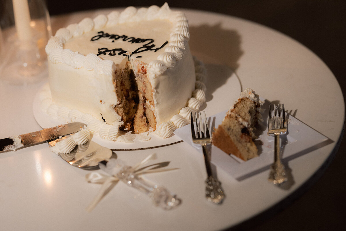 Editorial wedding photographer captures a classic and candid moment of the wedding cake cutting, showcasing refined, timeless elegance.