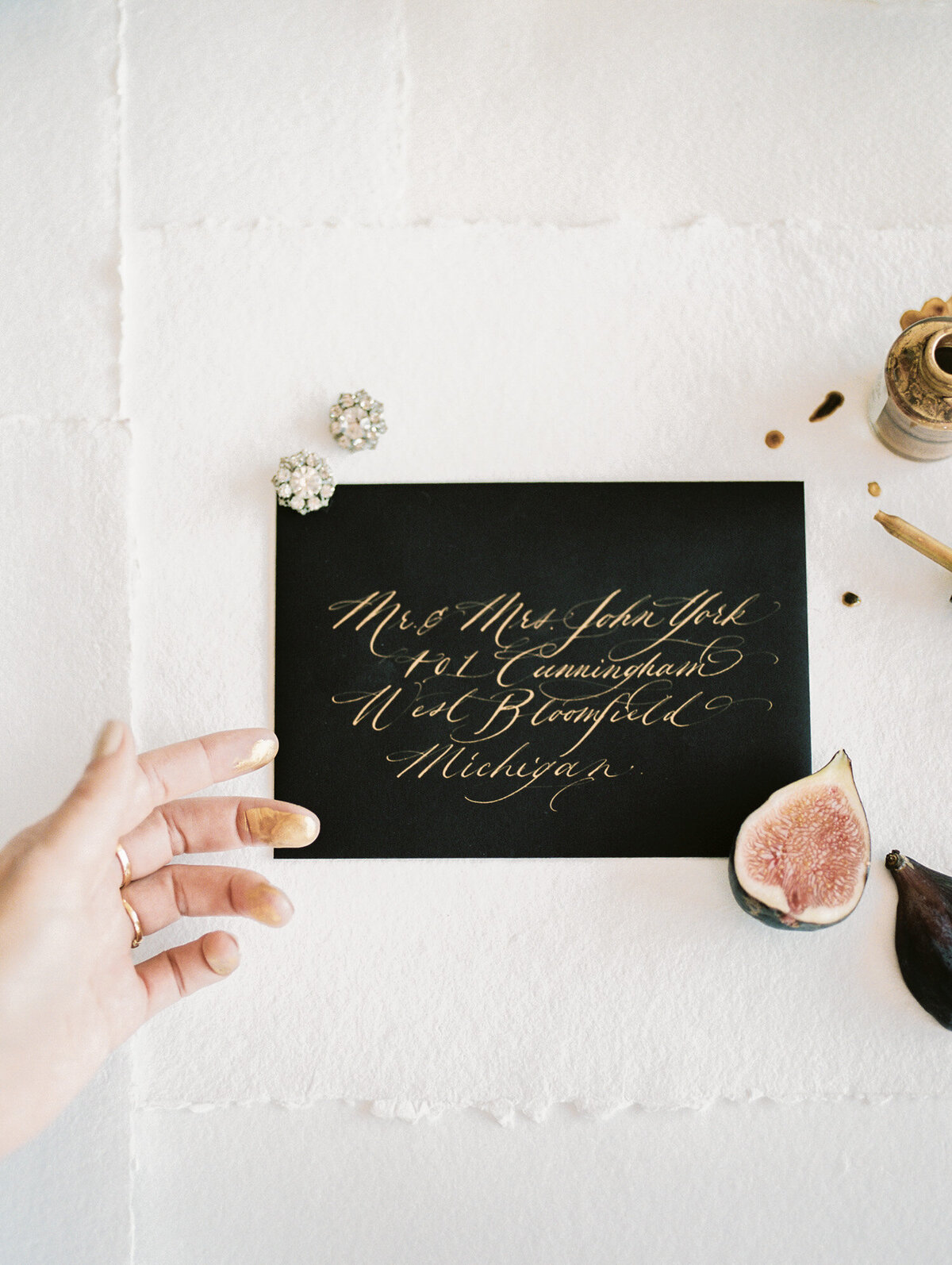 black envelope with gold ink calligraphy, diamond antique jewelry, figs, film calligrapher brand photo