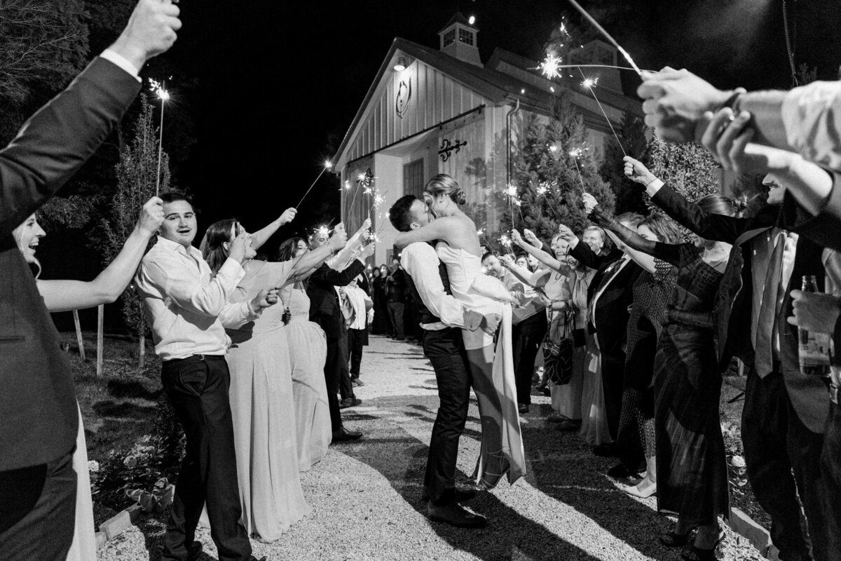 Newlywed couple walking through a sparkler send-off at night.