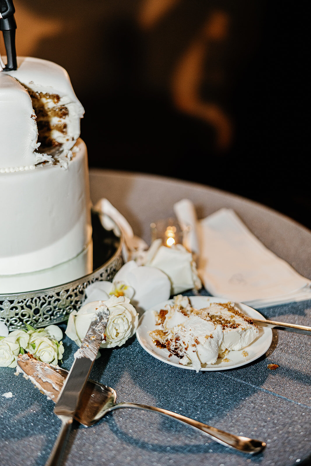 A detailed shot of the couple's wedding cake slice, adorned with white orchids and surrounded by elegant table decor, taken at Ocean Reef, Key Largo.