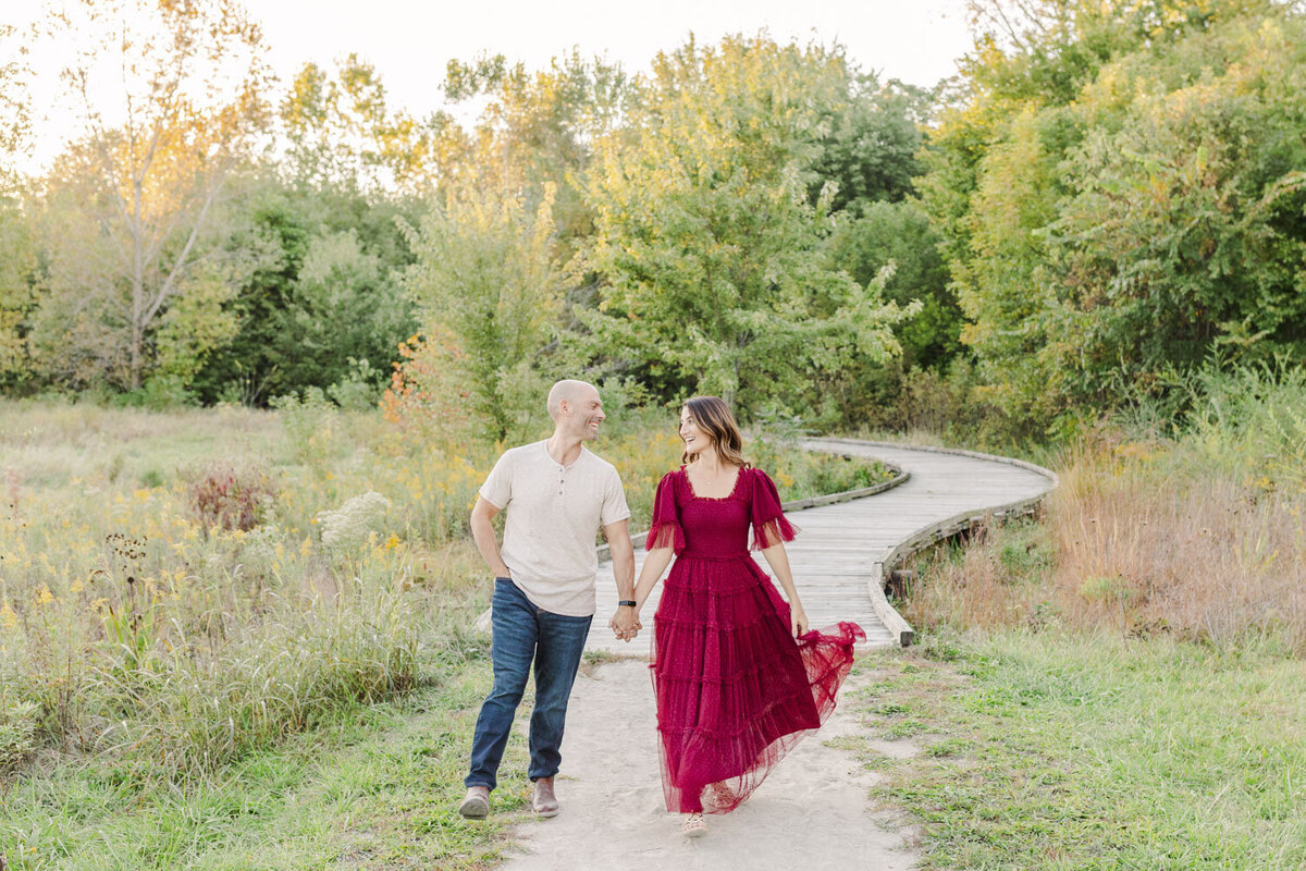 couple holding hands while walking on a nature trail