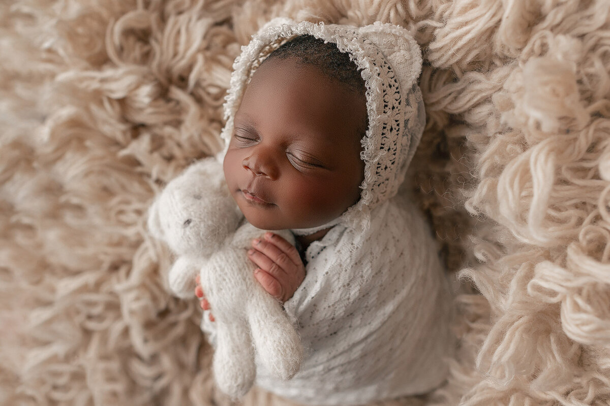 adorable baby wrapped up wearing teddy bear bonnet