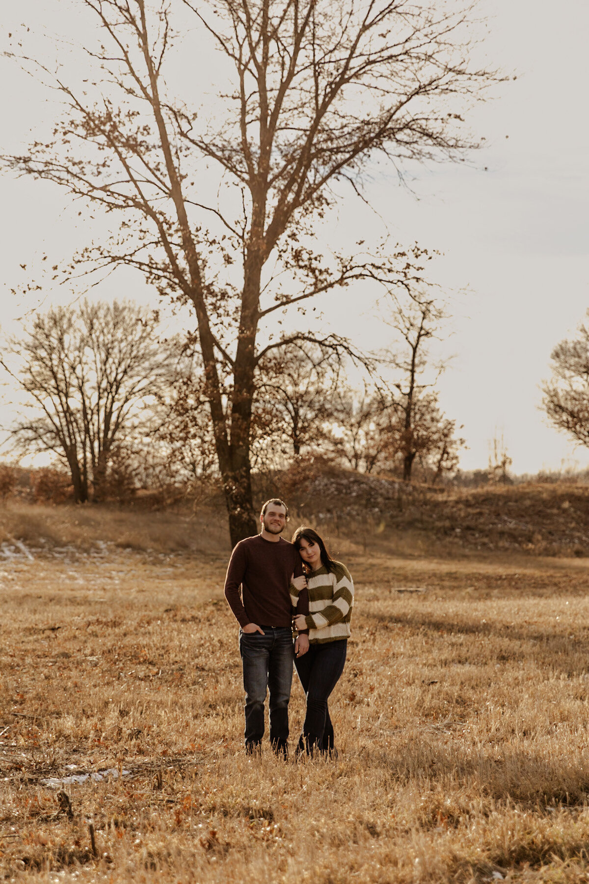 Engaged couple standing in a field of grass posing captured by a Minnesota Couples Photographer