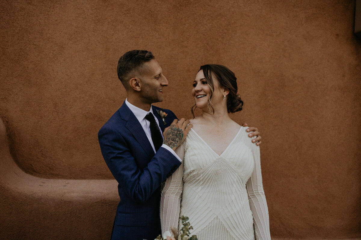 bride and groom in front of an adobe style building in Santa Fe