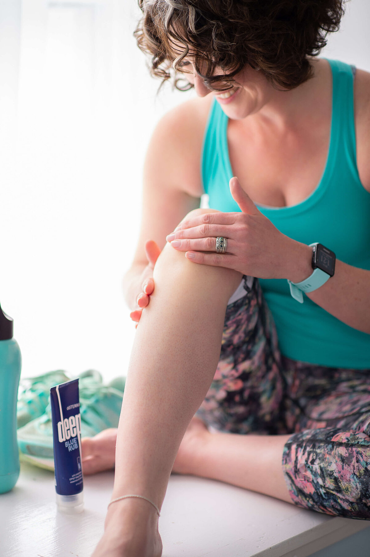 ottawa brand photos showing a woman in blue workout top and tights rubbing DoTerra deep blue rub on her legs