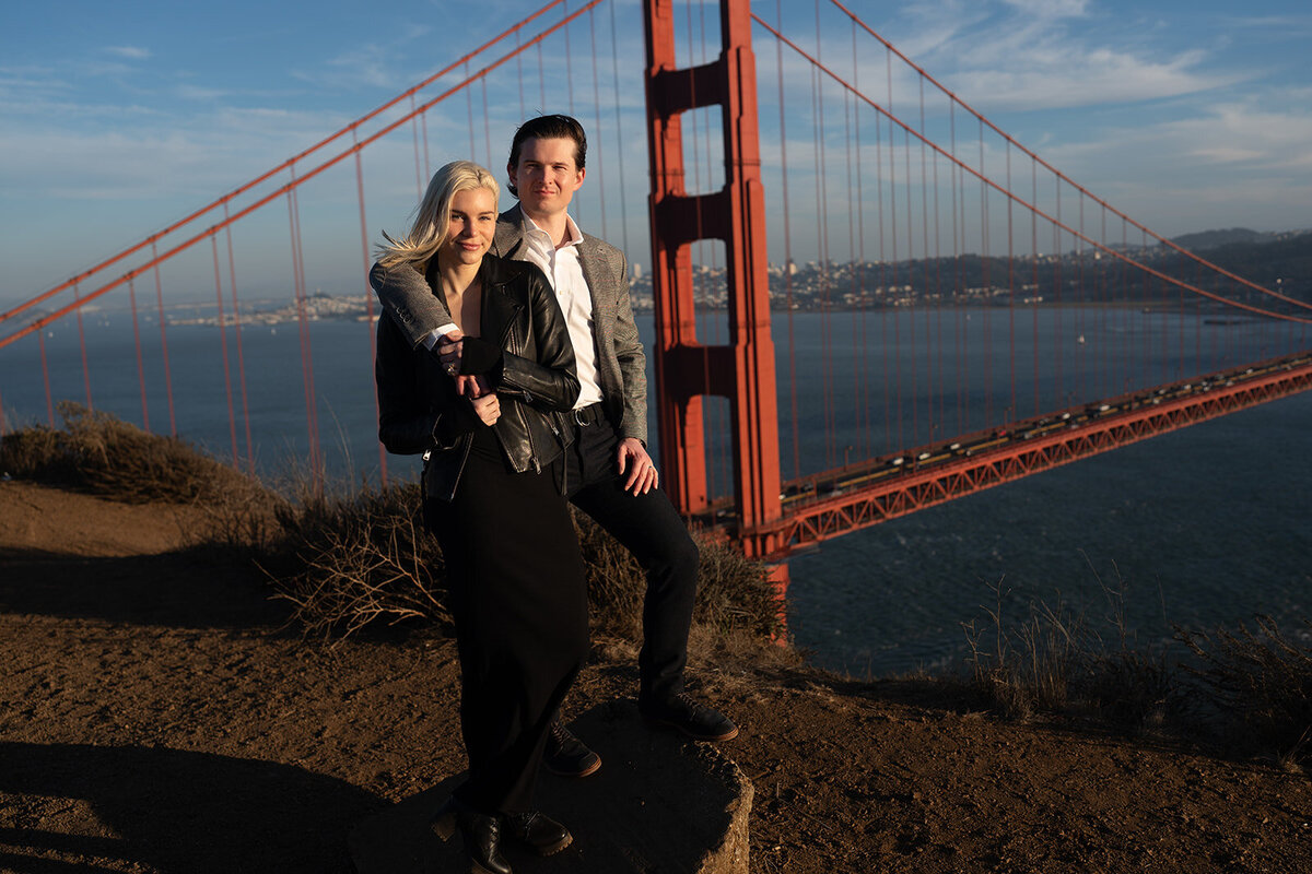 Couple posing at sunset over the golden gate bridge