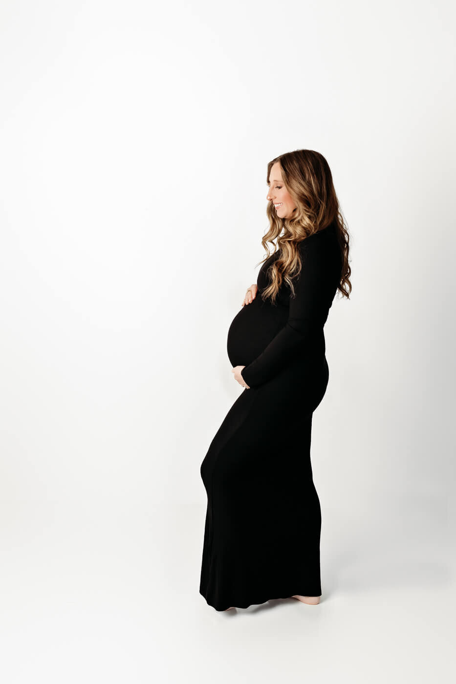 Maternity session in studio mom dressed in black cradling baby bump