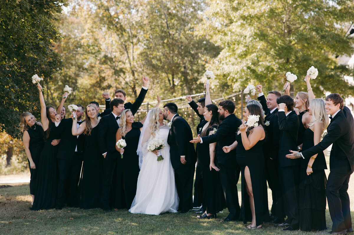 bridal party portrait of bride and groom kissing