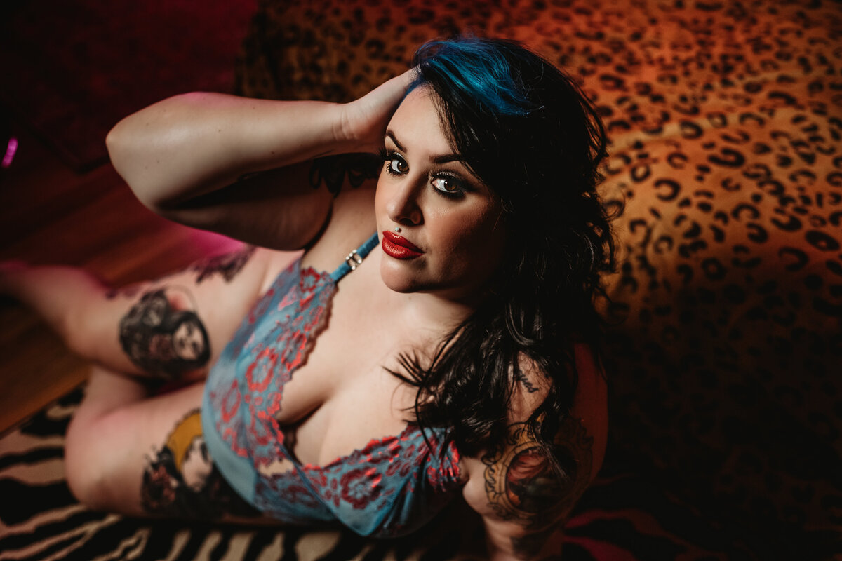 in home boudoir session with woman with blue hair laying across an animal print rug captured by Baltimore photographers