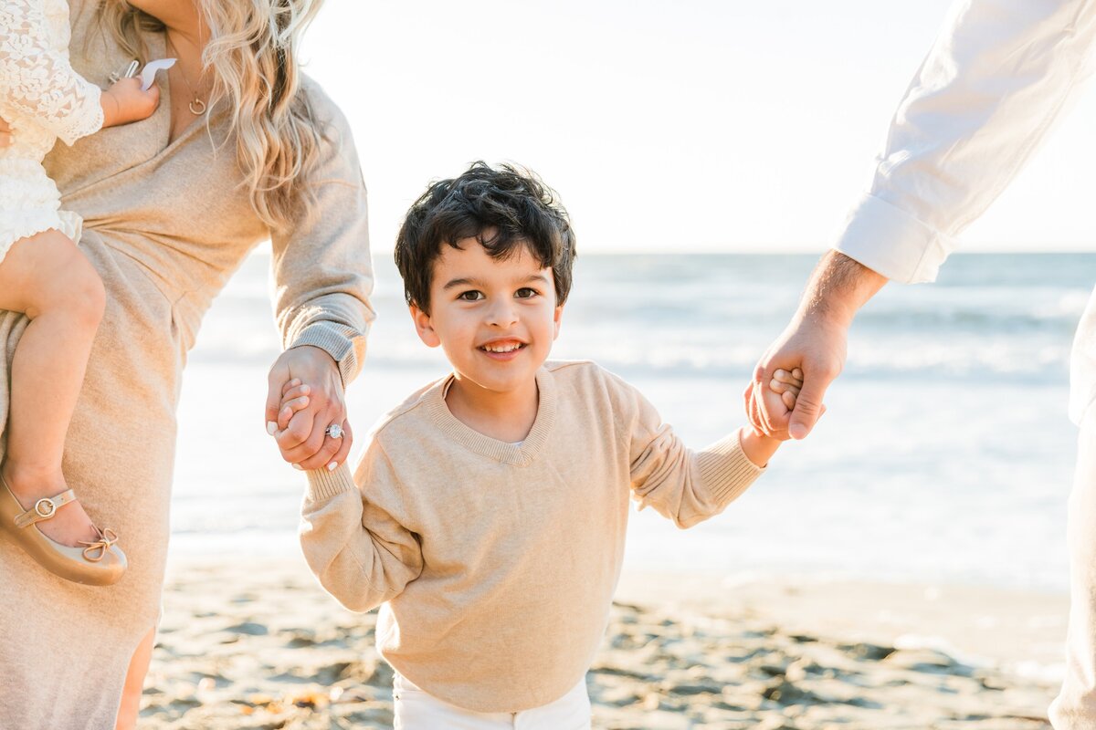 little-boy-holding-parents-hands-at-rat-beach