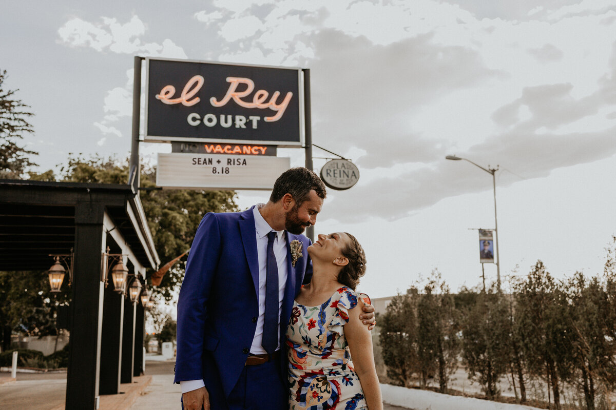 bride and groom stand in front of El Rey Court sign in Santa Fe featuring their names and wedding date