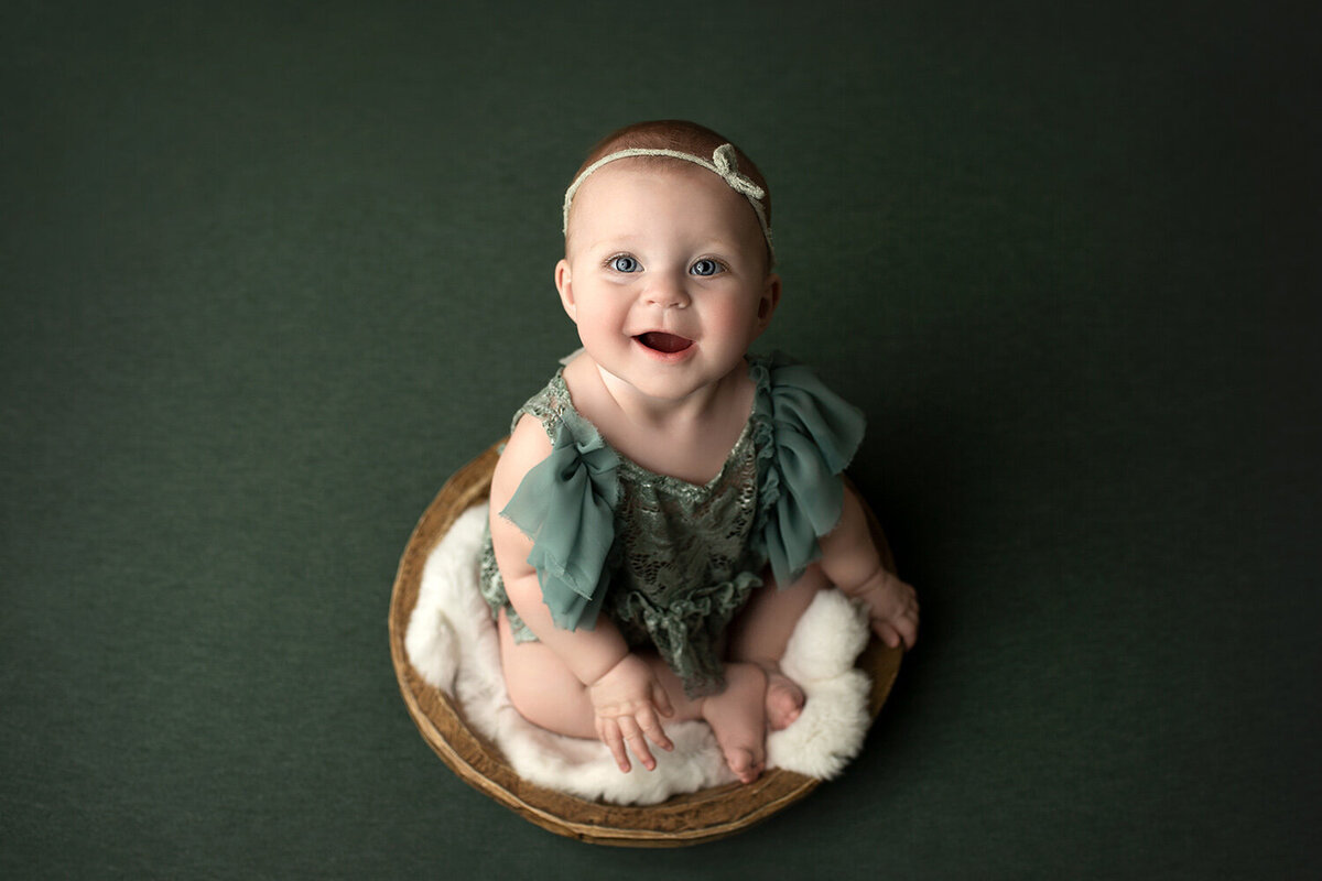 baby girl in boho basket smiling at camera