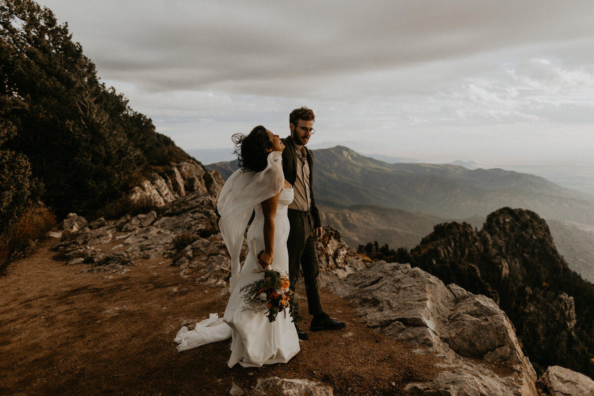 bride and groom looking down at the city of Albuquerque from the Sandia Mountains