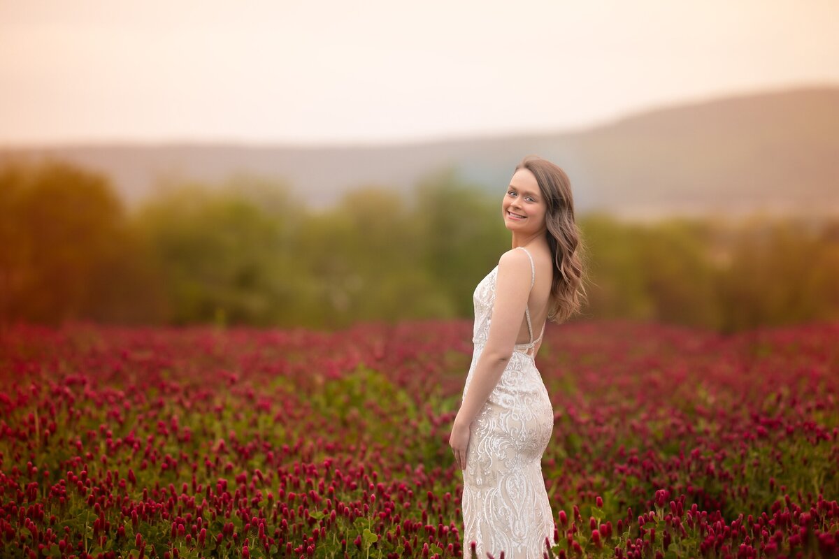 senior girl in white dress in crimson clover field