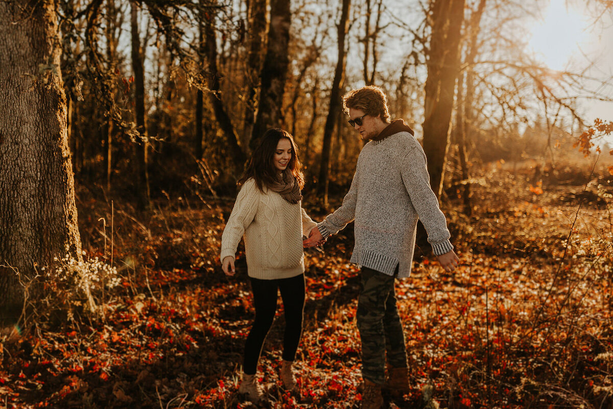 Couple standing surrounded by trees while holding each other's hand