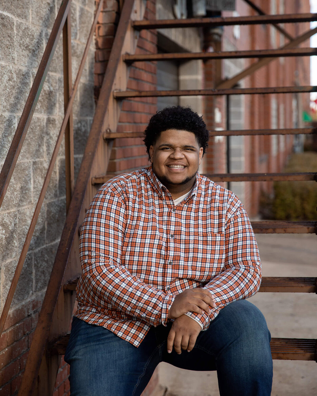Senior boy sitting on a metal staircase.