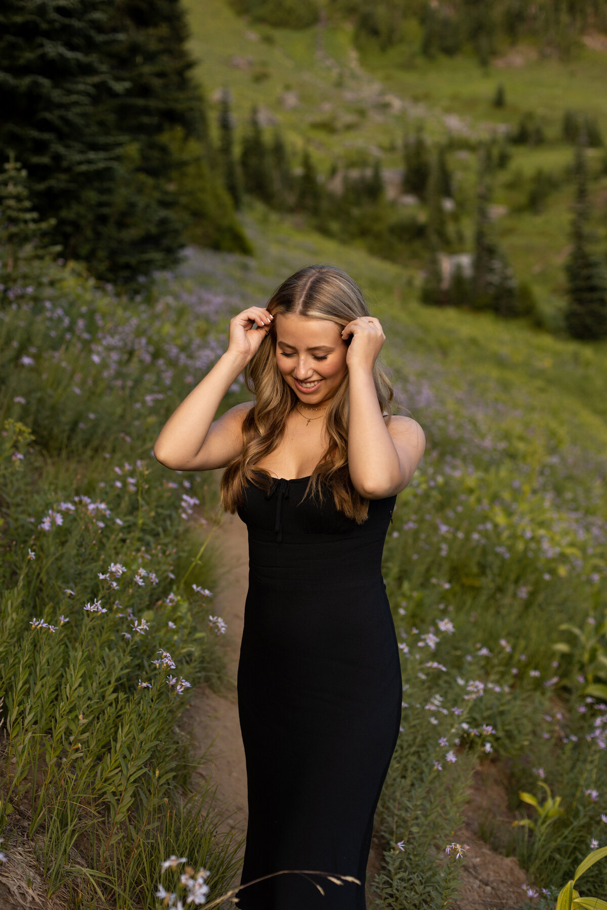 senior girl with purple wildflowers on each side of her hands up and bent putting her hair behind her ears