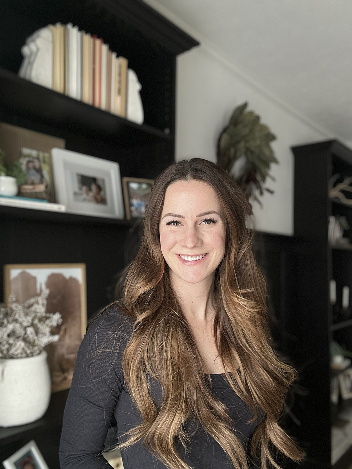 Jessica wearing a white blazer, smiling as she writes in her planner