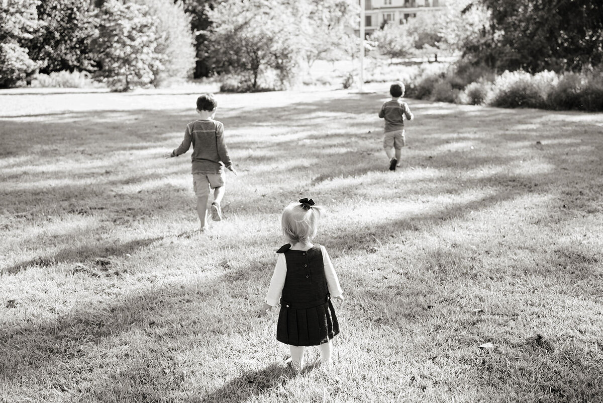 Three young children running in a park 